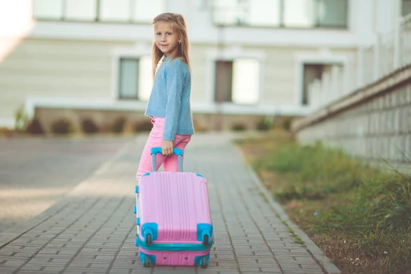 Счастливая маленькая девочка с розовым чемоданом готова к отпуску — стоковое фото