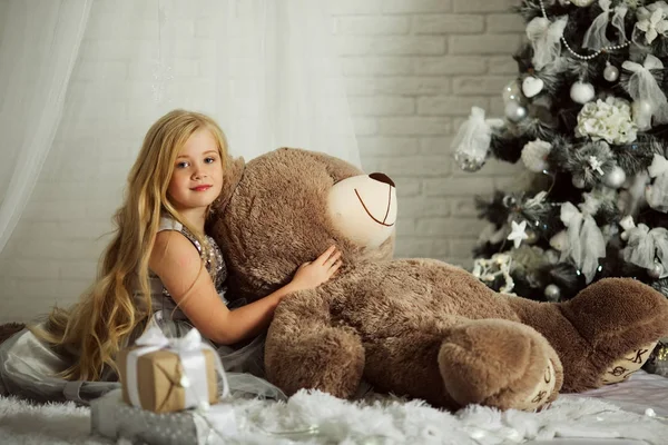 Καλά Χριστούγεννα και καλές διακοπές. Όμορφη ξανθιά κοπέλα με μακριά μαλλιά κρατά μεγάλο αρκουδάκι — Φωτογραφία Αρχείου