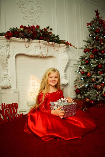 Portrait de jolie fille blonde aux cheveux longs porte une robe rouge mode près de l'arbre de Noël décoré — Photo