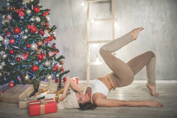 Güzel, esnek genç bir kadın Noel ağacı, spor ve tatil konsepti yakınında spor yapıyor. — Stok fotoğraf