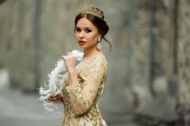Güzel seksi kadın moda makyaj ile Prenses elbise ve beyaz tüy tutan taç giyiyor