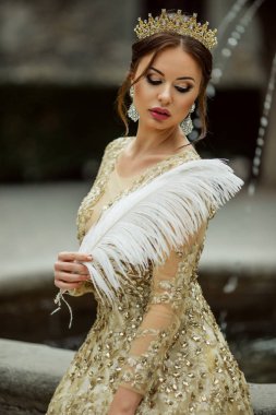 Güzel seksi kadın moda makyaj ile Prenses elbise ve beyaz tüy tutan taç giyiyor