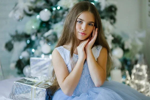 Retrato de hermosa chica está sentado cerca del árbol de Navidad decorado con caja de regalo de plata —  Fotos de Stock