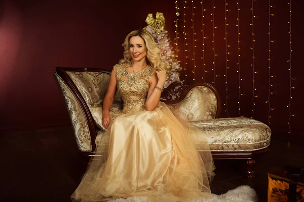 Красивая блондинка носит модное золотое платье на елку — стоковое фото