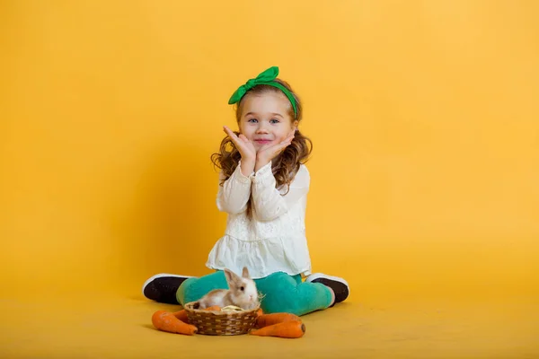 Досить щаслива дитина дівчина з моркви і її друг мало барвисті кролика Великодні свята концепції — стокове фото