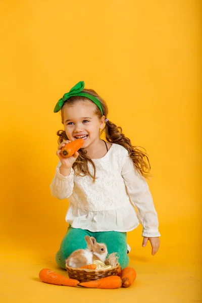 Vrij gelukkig kind meisje is het eten van worteltjes en haar vriend beetje kleurrijke konijn, concept van Pasen vakantie — Stockfoto