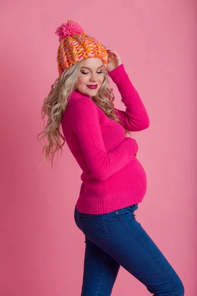 따뜻한 겨울 옷 모자와 스웨터 핑크에 고립 된 금발 임신한 여 자가 입으십시오 — 스톡 사진