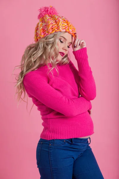 Kaunis onnellinen raskaana oleva nainen on yllään lämmin talvivaatteita hattu ja pusero eristetty vaaleanpunainen tausta — kuvapankkivalokuva