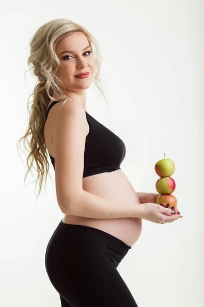 Gravid sportig kvinna med gröna äpplen isolerad på vit — Stockfoto