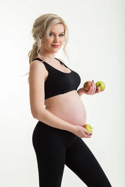 Mujer hermosa deportiva embarazada con manzanas verdes aisladas en blanco — Foto de Stock