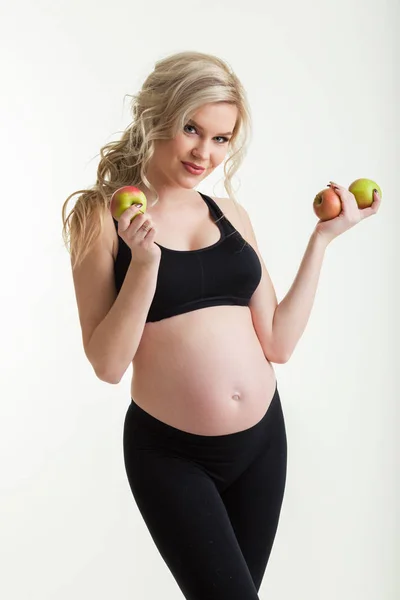 Mujer hermosa deportiva embarazada está sosteniendo manzanas verdes aisladas en blanco, concepto de alimentos saludables — Foto de Stock