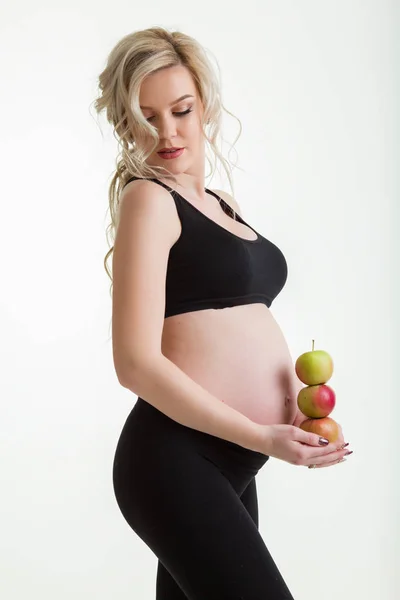 Piękna kobieta w ciąży ma na sobie ubrania sportive gospodarstwa zielone jabłka na białym tle na białe, zdrowe jedzenie koncepcja — Zdjęcie stockowe