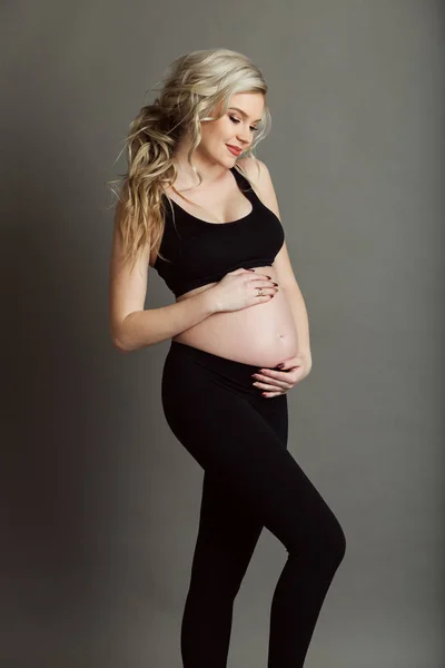 Piękna kobieta w ciąży ma na sobie sportive czarne ubrania na białym tle na koncepcji szary, zdrowe życie — Zdjęcie stockowe