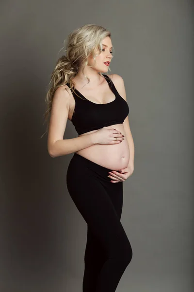 怀孕漂亮的金发女人穿着黑色的衣服, 在灰色, 健康的生活概念隔离 — 图库照片