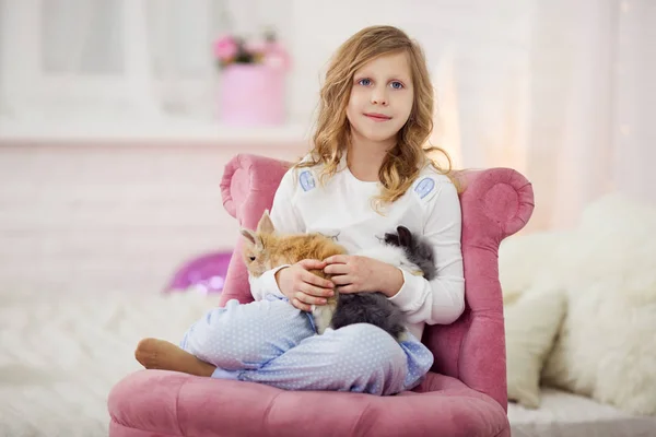 Pretty little girl at home is playing with rabbit — Stock Photo, Image