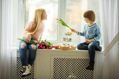 Güzel çocuklar, sevimli bir kız Lale Pembe çiçek vererek mutlu küçük çocuk. Paskalya kavramı