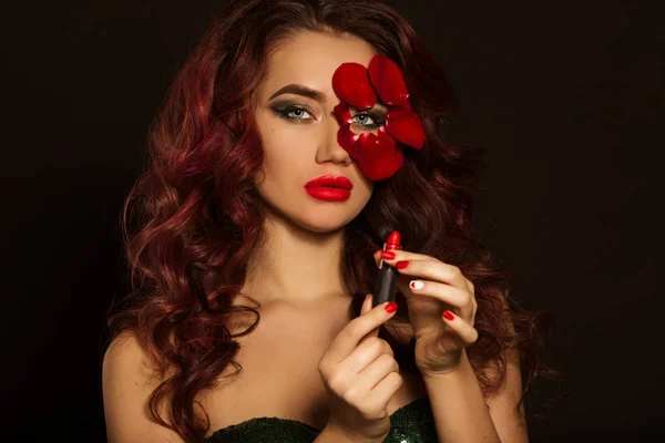 Sexy señora de la moda con maquillaje creativo y pétalos de rosa de su cara está sosteniendo lápiz labial rojo, concepto de cosméticos —  Fotos de Stock