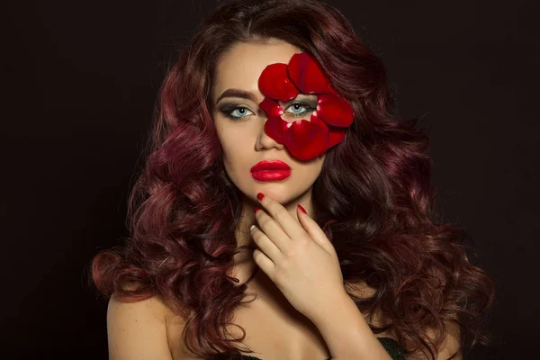 Портрет красивой роскошной сексуальной женщины с креативным макияжем и красными лепестками роз ее лица — стоковое фото