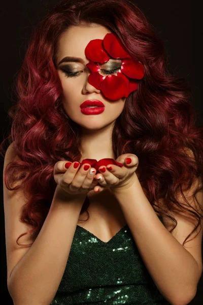 Портрет красивой роскошной сексуальной женщины с творческим макияжем и красными лепестками роз ее лица и в руках — стоковое фото