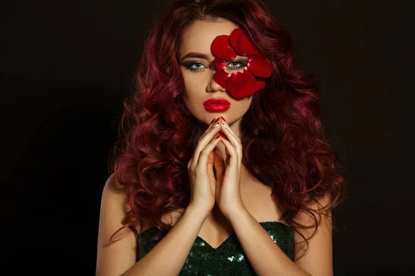 Portrait de belle femme sexy de luxe avec maquillage créatif et pétales de rose rouge de son visage porte une robe verte brillante — Photo