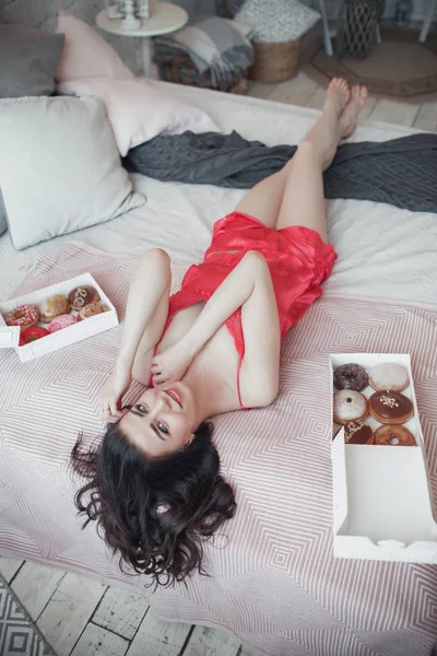 Bella ragazza sexy sottile è sdraiata a letto con le gambe alzate, ora di colazione, concetto di buongiorno — Foto Stock