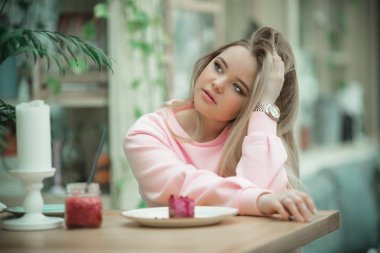 Güzel sarışın kız kafe ve kırmızı meyve suyu içme verandada oturuyor