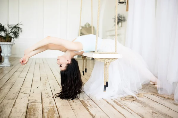 Молода красива балерина сидить на гойдалках в студії — стокове фото