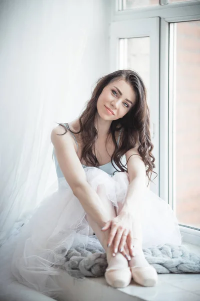 Hermosa bailarina chica está sentado en el alféizar de la ventana en el estudio —  Fotos de Stock