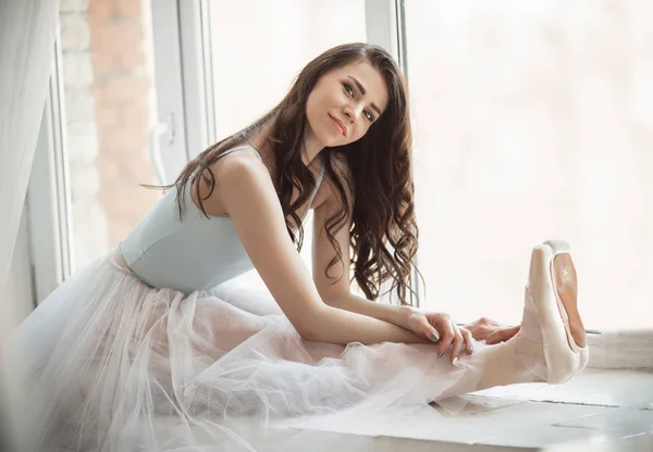 Hermosa bailarina chica está sentado en el alféizar de la ventana en el estudio —  Fotos de Stock