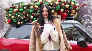 Güzel genç kız kırmızı arabanın yanında süslü kostüm ağacıyla maytaplarla oynuyor..