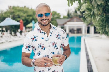 Maldivler 'in tatil köyünde bir bardak sarıyla gezen yakışıklı bir adam.