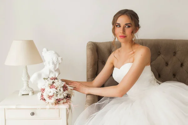 Молода наречена в красивій сукні сидить вдома з гарним білим інтер'єром. Весільна концепція . — стокове фото