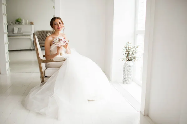 Молода наречена в розкішній сукні тримає букет квітів у яскраво-білій студії. концепція весільної моди . — стокове фото