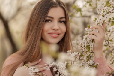 Kiraz bahçesinde bahar çiçekleri açan güzel doğal bir kadın..