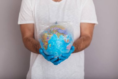 Elçi, eldiven takıyor. Plastik torbada küre tutuyor. Dünya çevre günü konseri. Dünya gezegeninin tehlikeli zehirli plastik çöplerden arındırılmasının sembolü. İzole edilmiş beyaz arkaplan