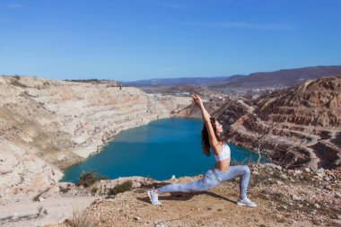 Genç zayıf kadın dağ gölünde yoga yapıyor.