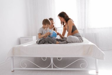Mutlu aile annesi, kızı ve oğlu beyaz yatak odasında eğleniyor. Evde kalıp konsept yapın..