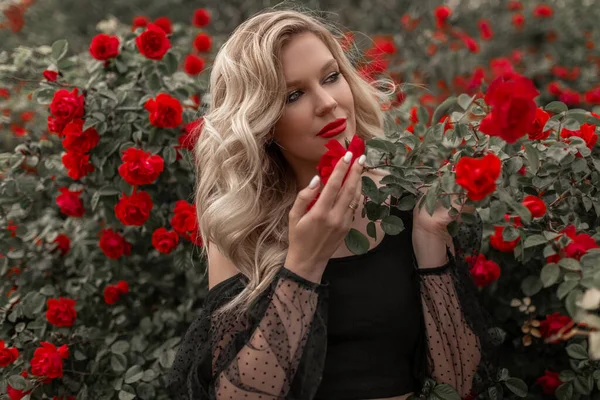 美丽的金发女子在花园与红玫瑰 春天的时间 — 图库照片
