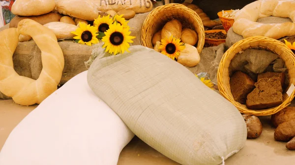 Composition of rye breads, bag  flour and baguettes with sunflowers on wooden table