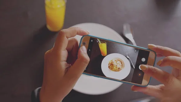 Female hand taking some photos from her mobile of a delicious italian food dish. close up