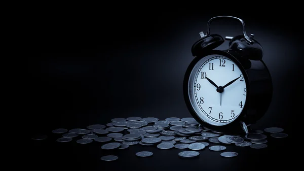 Εξοικονόμηση χρόνου, ρολόι-ξυπνητήρι με νομίσματα απομονωμένες σε μαύρο φόντο. με vintage φίλτρο — Φωτογραφία Αρχείου