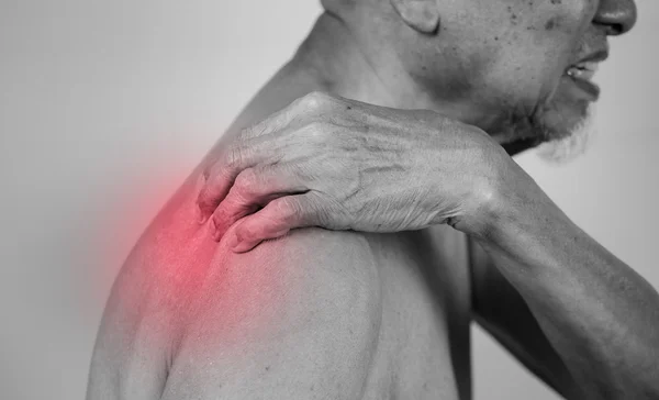 Hombre mayor sosteniendo el hombro en el área del dolor con efecto rojo —  Fotos de Stock