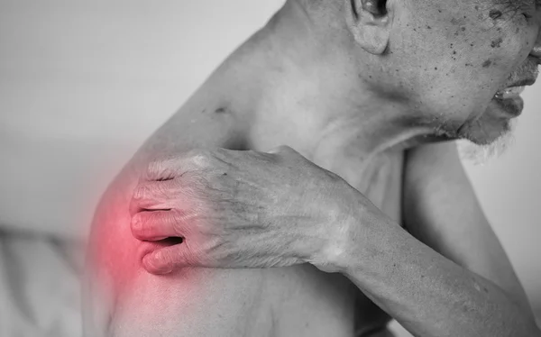 Hombre mayor sosteniendo su hombro en la zona del dolor. efecto rojo — Foto de Stock