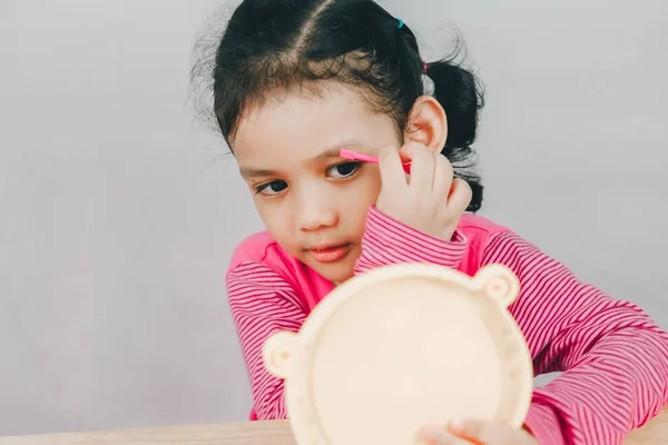 Ásia menina jogar pintado sua sobrancelha com espelho — Fotografia de Stock