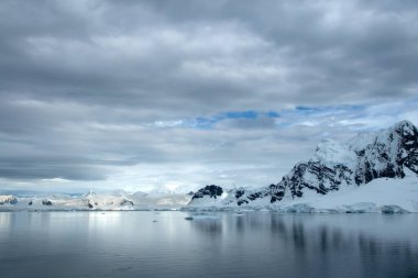 Antarktika 'daki dağ sıraları, okyanusta yüzen buz dağları ve karla kaplı..