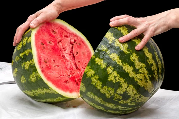 Handen van twee helften van watermeloen — Stockfoto