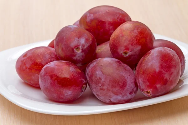 Rote reife Pflaume auf dem weißen Teller — Stockfoto