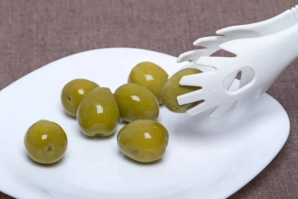 Large green olives and tongs — Stock Photo, Image