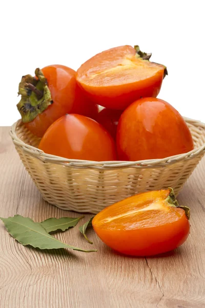 Persimmon in a wicker bowl — Stock Photo, Image
