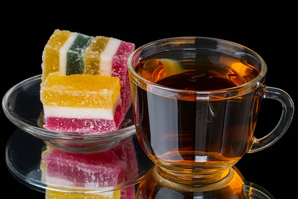 Чашка чая с фруктовыми конфетками на черном — стоковое фото